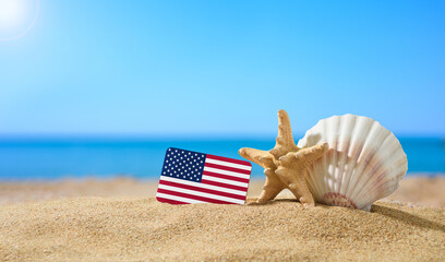 Tropical beach with seashells and flag of the United States. The concept of a paradise vacation on the beaches of USA.