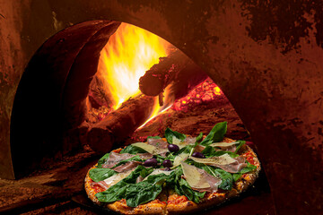 .Pizza coming out of the wood oven. Flavor: mozzarella, Parma ham, Parmesan cheese, arugula, black...