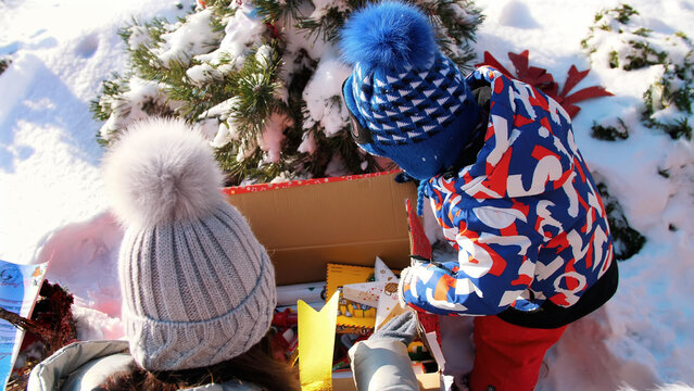 winter, frosty, snowy, sunny day. Happy family with small children unpack boxes with gifts under the Christmas tree, outdoors. High quality photo