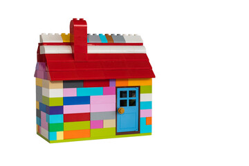Colorful house made with toy from plastic blocks. Chimney, roof and door. White background with space for text.