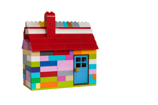 Colorful house made with toy from plastic blocks. Chimney, roof and door. White background with space for text.
