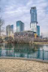 Austin Texas downtown skyline against cloudy sky with pond and park scenery