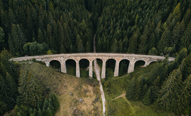 Fototapeta na wymiar Railway bridge - Viaduct of Telgart in Europe Slovakia from above (top view) with beautiful pine forest and path under the viaduct. Aerial photo of train railways by drone - wide angle view.