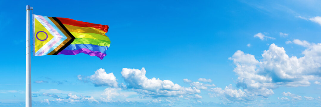 New LGBTQ Pride  flag waving on a blue sky in beautiful clouds - Horizontal banner
