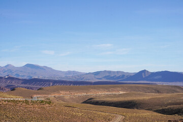 Fototapeta na wymiar Paisaje de serranía (mountain range) camino entre Uyuni y Potosí (Potosi) con carretera en el medio y montañas de fondo 