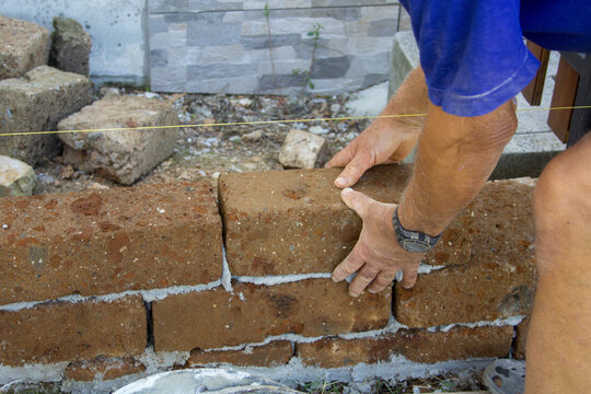 Image Of The Hands Of A Bricklayer Who Builds A Wall With Tuff Bricks Following The Thread For Accuracy. DIY Building Constructions
