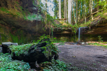 natürlicher Wasserfall mit Felsen und grünen Moos im Pfälzer Wald in Deutschland