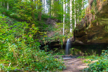 Natürlicher Wasserfall mit Steinen und grünen Moos