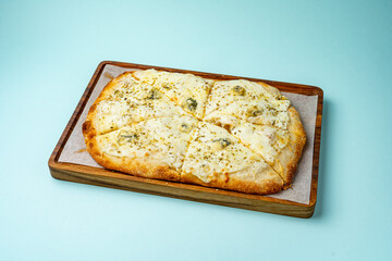 four cheese pizza on a wooden board on a colored background