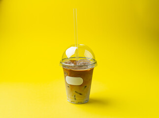 frappe in a plastic glass with a straw on a yellow background
