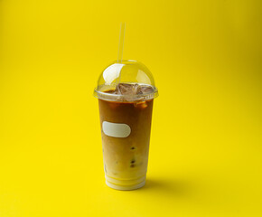 frappe in a plastic glass with a straw on a yellow background