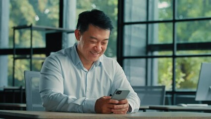 Male portrait asian chinese man entrepreneur employer work in office look at modern gadget phone mobile screen search information online use smartphone apps technology 5g wi-fi online communication - Powered by Adobe
