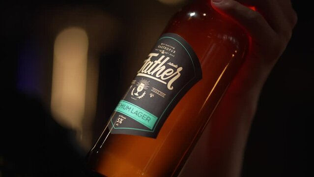 A man holds a bottle of light beer with a name label in his hands