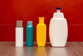 Containers and bottles of different sizes, shapes and colors for cleanser, tonic, conditioner, soap and shampoo on a red background in the bathroom. Natural organic cosmetics, packaging with an empty.