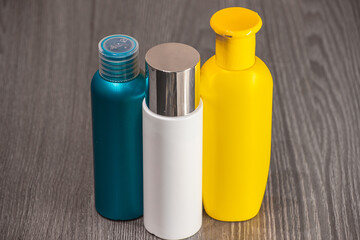 Plastic bottles of various sizes, shapes and colors for detergent, tonic, conditioner, soap and shampoo on a wooden table. Natural organic cosmetics, packaging with an empty label.