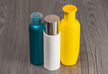 Plastic bottles of various sizes, shapes and colors for detergent, tonic, conditioner, soap and shampoo on a wooden table. Natural organic cosmetics, packaging with an empty label.