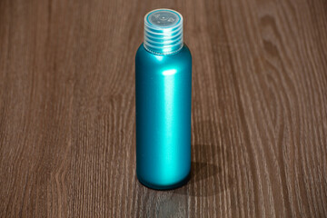 A green plastic bottle for detergent, tonic, conditioner, soap and shampoo on a wooden table. Natural organic cosmetics, packaging with an empty label.