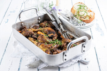 Traditional French poulet basquaise with chicken and vegetable in red wine sauce served with baguette as close-up in a design casserole