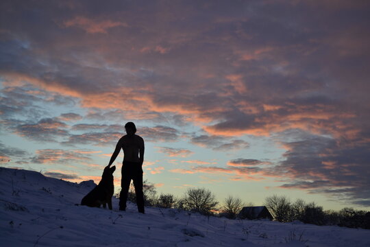 man with dog in winter at sunset