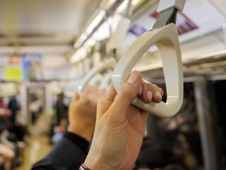 Hands holding on to handles to support themselves while standing on a busy subway train - 540136775