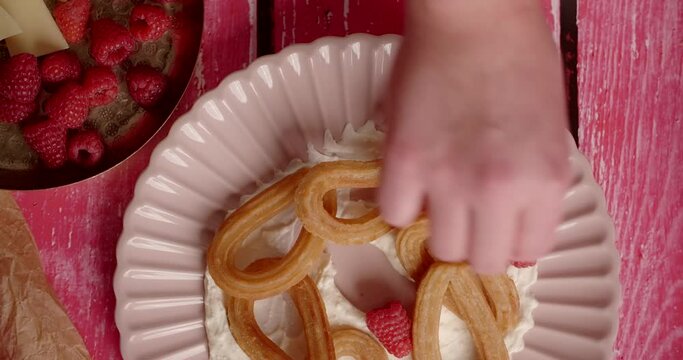Flat lay food recipe: chef puts raspberries to the plate with churos and cream