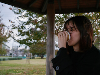 A beautiful Japanese lady drinking coffee in a park - 540137100