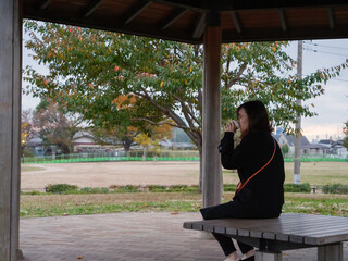 A young Asian lady sat a bench by herself - 540138301