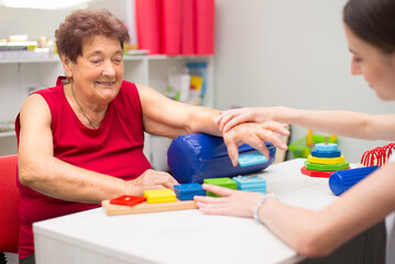 Old woman suffering from stroke exercising on physiotherapy with help of physiotherapist in the hospital