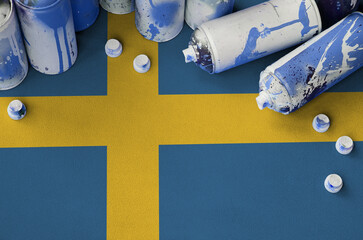 Sweden flag and few used aerosol spray cans for graffiti painting. Street art culture concept