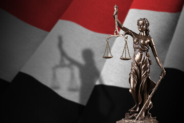Yemen flag with statue of lady justice and judicial scales in dark room. Concept of judgement and...