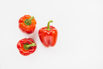 Three sweet red bell peppers on white background. Top view, copy space