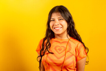 Enlightened positive brunette woman smiling, wears orange t-shirt, has good mood, latina female,...