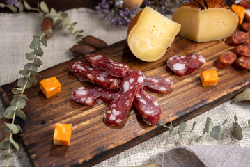 table of cold meats sausages salamin red chorizo sopresatta longaniza and various cheeses with craft knife and bread decorated with dried flowers wooden oil and pepper shaker