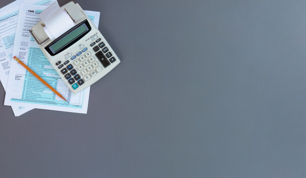 US Individual income tax return with retro calculator and pencil on gray desktop