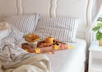 Wooden tray with breakfast and a garland in bed.