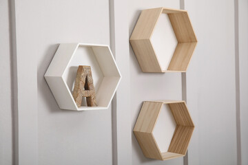 Honeycomb shaped shelves with decorative wooden letter on white wall