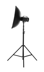 Studio flash light with reflector on tripod against white background. Professional photographer's equipment