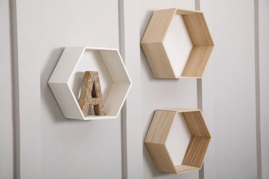 Honeycomb shaped shelves with decorative wooden letter on white wall