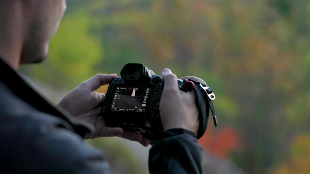 photographer taking landscape photos at the edge of a cliff at sunset. raises camera and lowers it back down