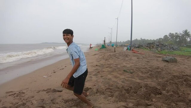 A teenage South Asian boy somersaults on the beach. free exercise.