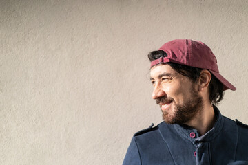 Close-up portrait of Latin man in profile smiling on a wall in a park