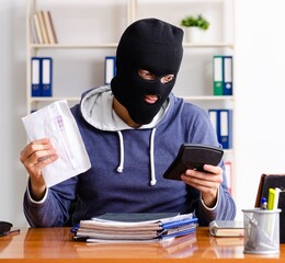 Male thief in balaclava in the office