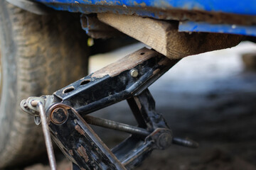 Defocus closeup of a car lifted on jack in process of new wheel tire replacement. Car jack. Lifting...