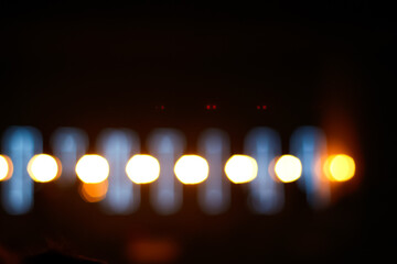 Defocus blurred abstract black and orange light bokeh background. Festive spotted glitter...