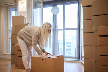 Young woman moving new place and repair concept - happy young woman with many cardboard boxes...