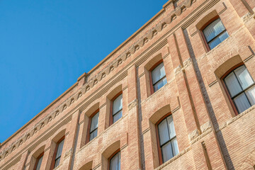 Fototapeta na wymiar Building exterior with rectangular windows and brick wall against blue sky