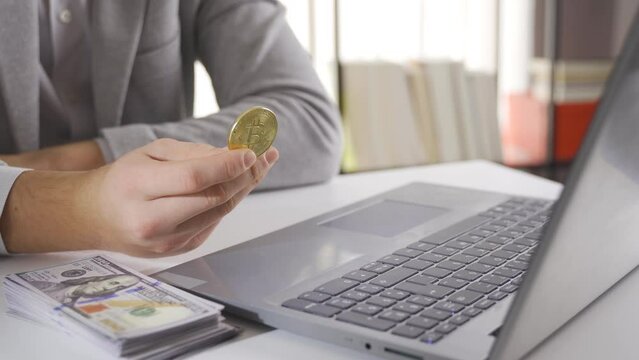 Bitcoin investment. Man following the stock market holding bitcoin and US dollars on the table.
Close-up businessman looking at bitcoin and stack of us dollars on the table.
