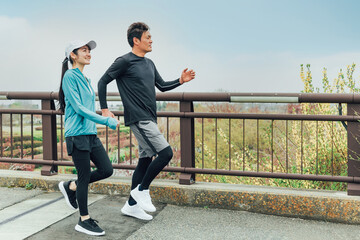 運動不足解消・ダイエットのため健康づくりで公園を歩くアジア人の男女
