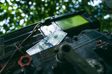 One hundred us dollars on a diesel engine of a minitractor close-up. Money and the agricultural...