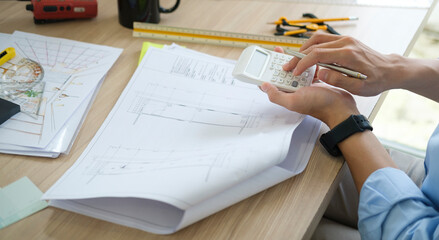 Cropped shot of architect inspecting architectural plan,  working with blueprints at workplace.
